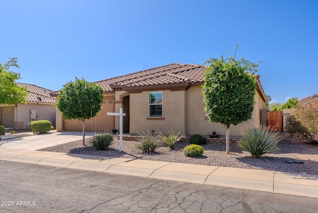 mediterranean / spanish house with stucco siding, fence, a tiled roof, driveway, and a garage