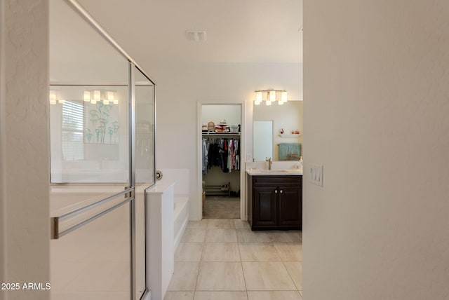 bathroom with tile patterned flooring, vanity, a walk in closet, a stall shower, and a garden tub