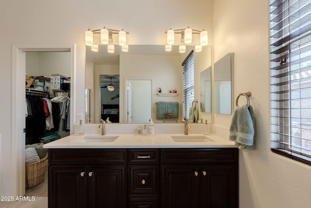 full bathroom with double vanity, a sink, and a walk in closet