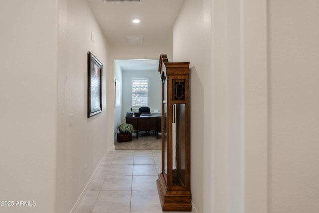 hallway with baseboards, visible vents, and light tile patterned flooring