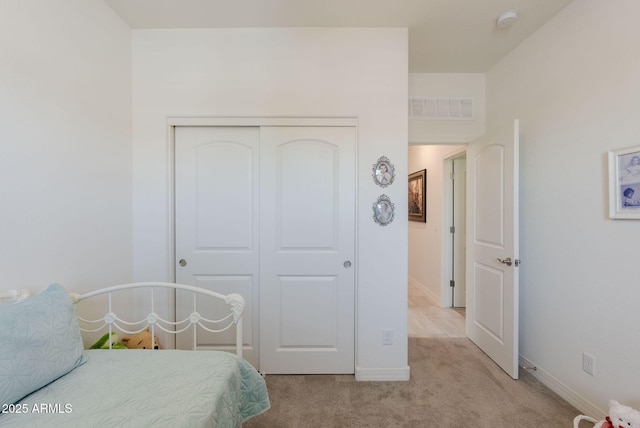 carpeted bedroom featuring baseboards, visible vents, and a closet