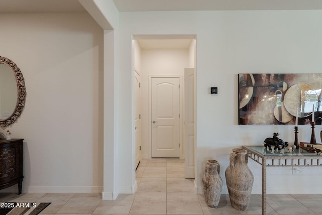 hallway featuring light tile patterned floors and baseboards