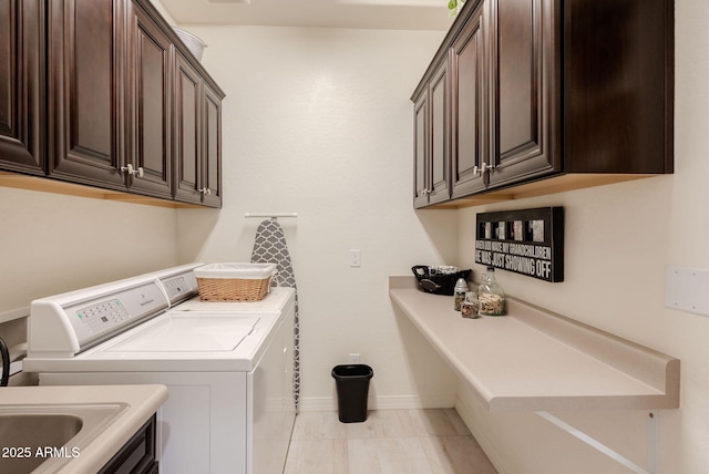 washroom featuring baseboards, washer and dryer, and cabinet space