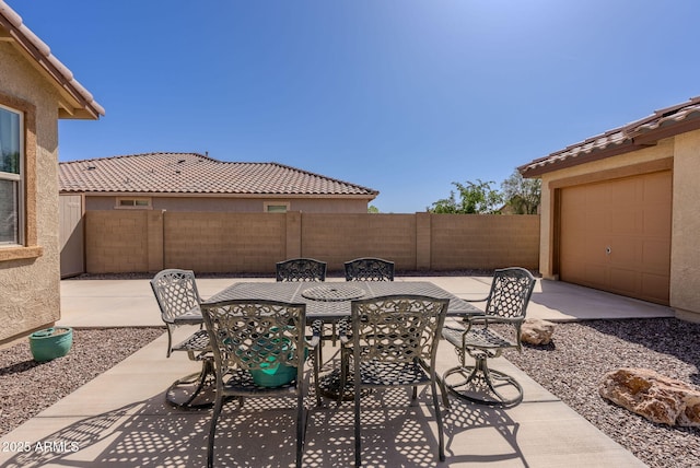view of patio featuring a garage, fence, and outdoor dining space