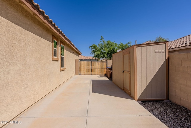 view of patio / terrace featuring a shed, an outdoor structure, and fence