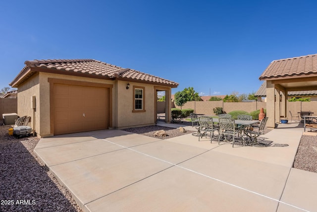 exterior space with driveway, outdoor dining area, fence, and a garage