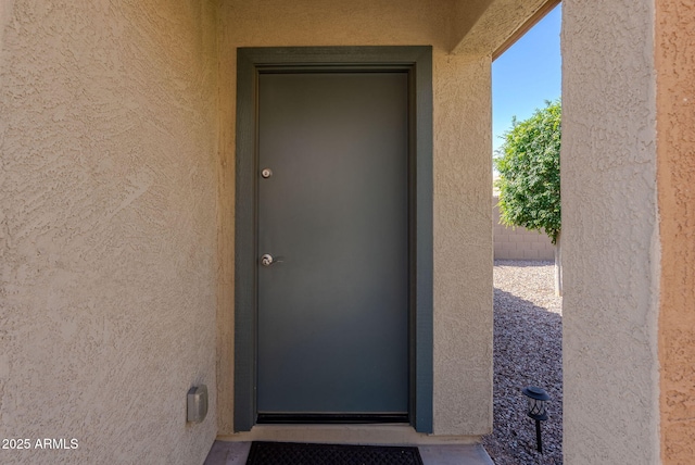 doorway to property with stucco siding and fence