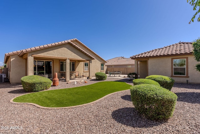 rear view of house featuring stucco siding, a tile roof, fence, and a patio