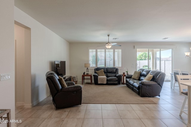 living area featuring light tile patterned floors, ceiling fan with notable chandelier, and visible vents
