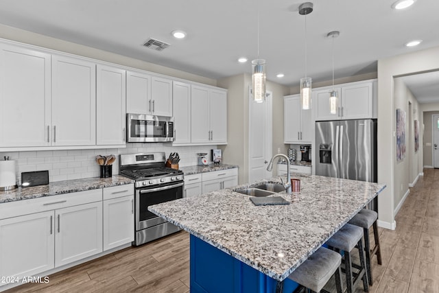 kitchen featuring light hardwood / wood-style floors, a kitchen island with sink, sink, white cabinets, and appliances with stainless steel finishes