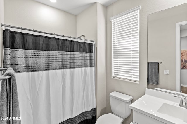 bathroom with a shower with curtain, vanity, toilet, and a healthy amount of sunlight