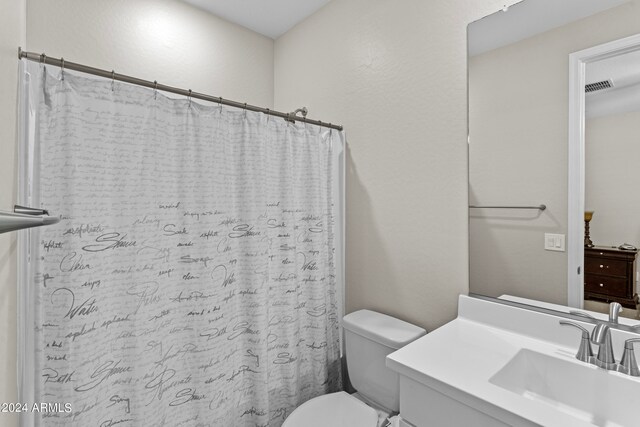 bathroom featuring toilet, vanity, and a shower with curtain