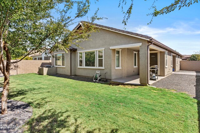 rear view of house featuring a yard and a patio