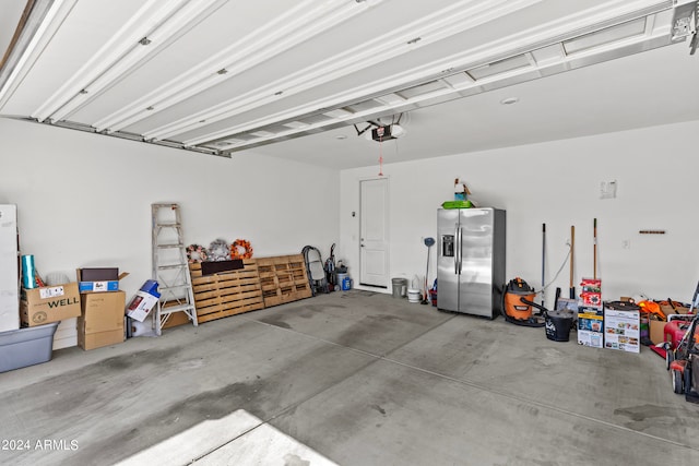 garage featuring a garage door opener and stainless steel fridge