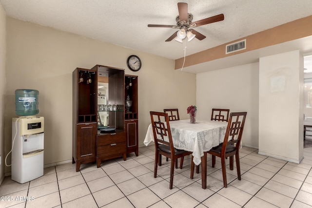 dining area featuring ceiling fan, light tile patterned floors, and a textured ceiling