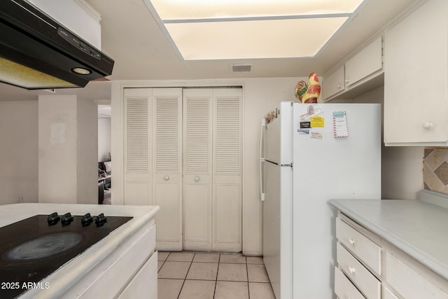 kitchen featuring white cabinetry, light tile patterned floors, black electric cooktop, and white fridge