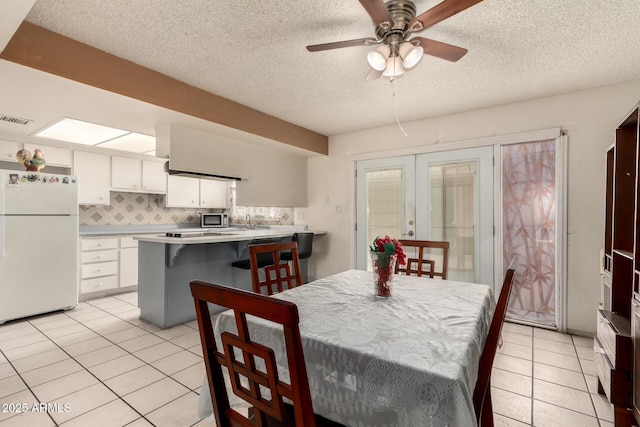 tiled dining area with ceiling fan, a textured ceiling, and french doors