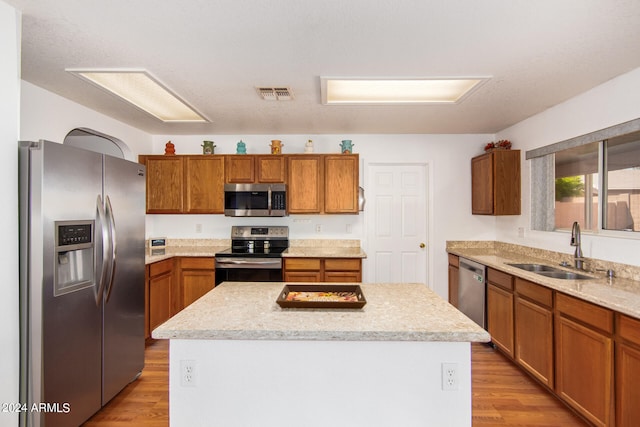 kitchen featuring a center island, stainless steel appliances, sink, and light wood-type flooring