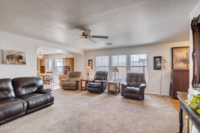 living room with a textured ceiling, ceiling fan, and carpet floors