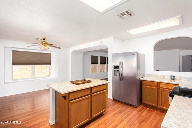 kitchen with a center island, light hardwood / wood-style floors, ceiling fan, stove, and stainless steel fridge with ice dispenser