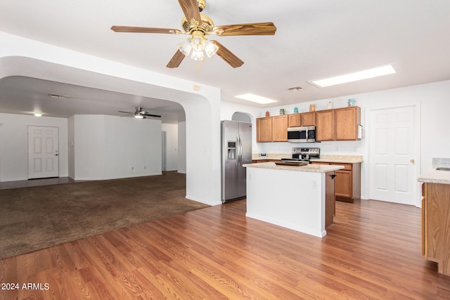 kitchen featuring ceiling fan, a kitchen island, stainless steel appliances, and light colored carpet