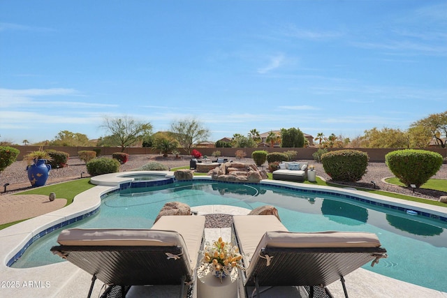 view of swimming pool with a fenced backyard and a pool with connected hot tub