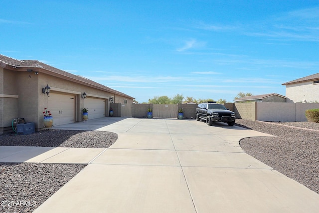 view of side of home with concrete driveway, fence, a gate, and stucco siding