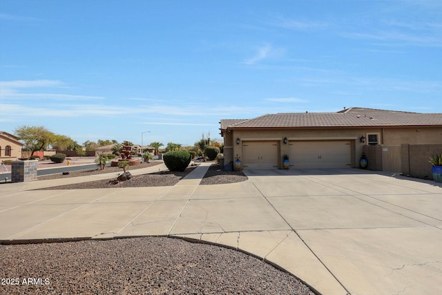 view of side of home featuring an attached garage, fence, concrete driveway, a tiled roof, and stucco siding