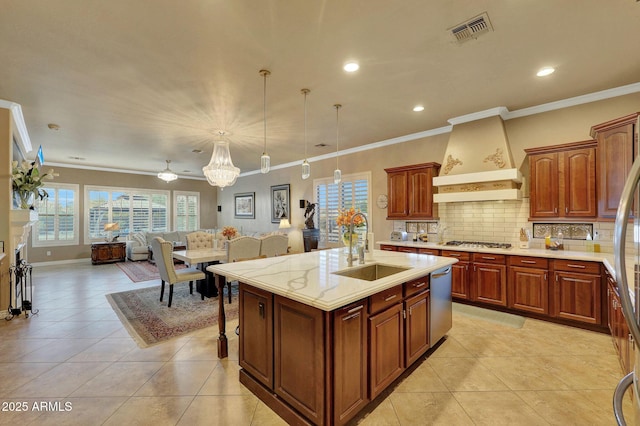 kitchen with visible vents, decorative backsplash, stainless steel appliances, premium range hood, and a sink