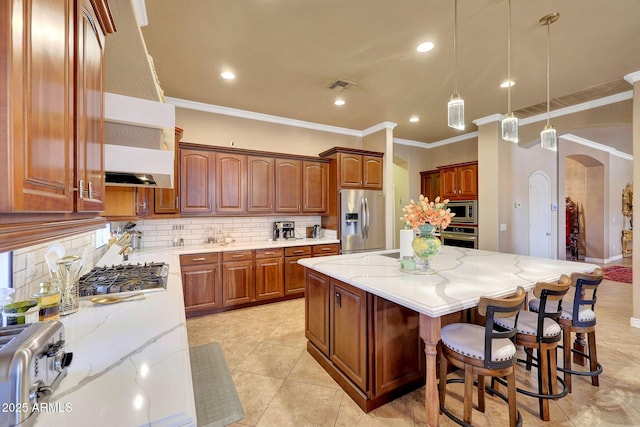 kitchen featuring visible vents, arched walkways, a center island, light stone countertops, and stainless steel appliances