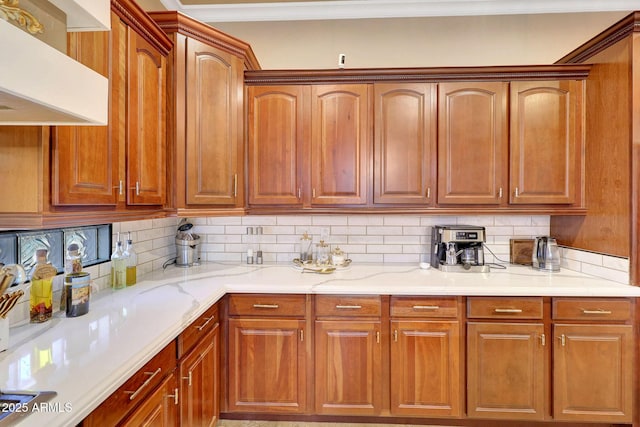 kitchen with decorative backsplash, brown cabinets, wall chimney exhaust hood, and light stone countertops