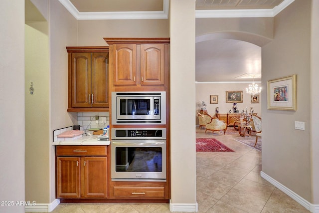 kitchen with appliances with stainless steel finishes, arched walkways, and ornamental molding