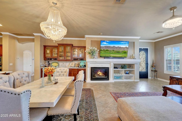 dining room with light tile patterned floors, visible vents, a notable chandelier, and a glass covered fireplace