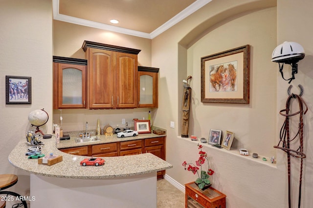 kitchen featuring brown cabinetry, light stone counters, a kitchen breakfast bar, a peninsula, and a sink