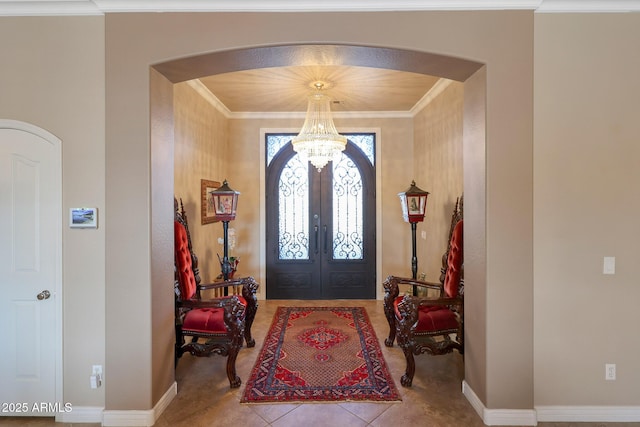 tiled foyer featuring baseboards, arched walkways, crown molding, french doors, and a chandelier