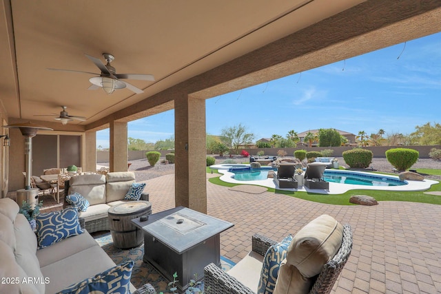 view of patio / terrace featuring a fenced backyard, an outdoor living space with a fire pit, a pool with connected hot tub, and a ceiling fan