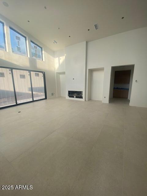 unfurnished living room featuring a fireplace and a towering ceiling