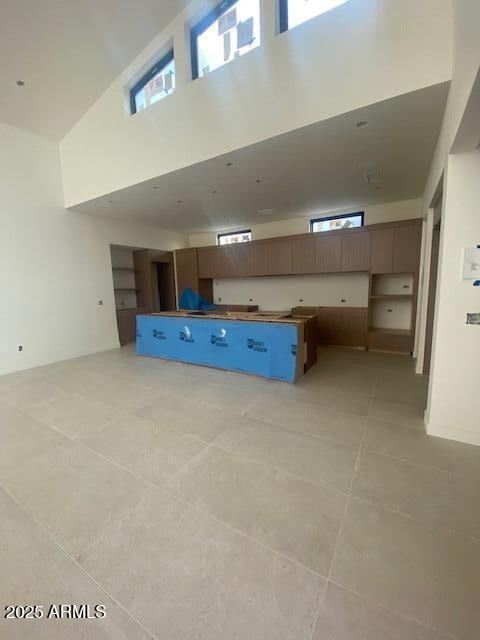 kitchen featuring a high ceiling, light tile patterned flooring, and open floor plan