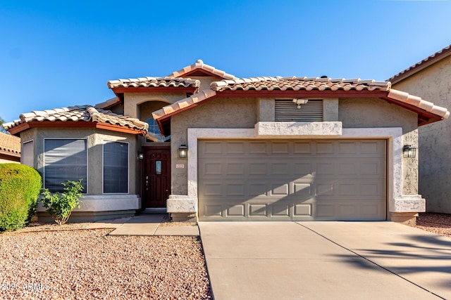 mediterranean / spanish-style home featuring an attached garage, concrete driveway, stucco siding, and a tile roof