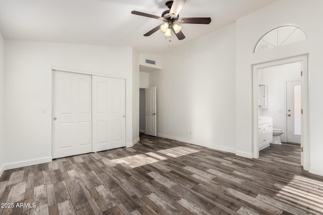 unfurnished bedroom featuring dark wood finished floors, a closet, baseboards, high vaulted ceiling, and ceiling fan