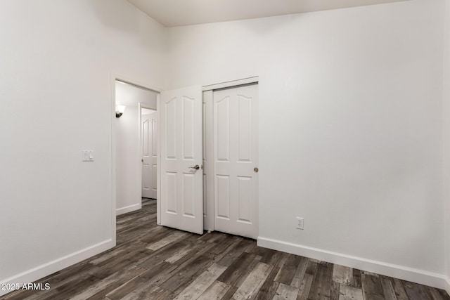 unfurnished bedroom with baseboards, dark wood finished floors, and a closet