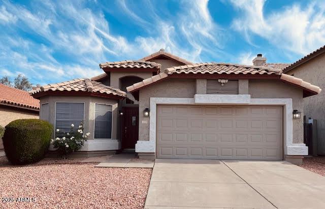 mediterranean / spanish-style home with an attached garage, driveway, stucco siding, and a tile roof