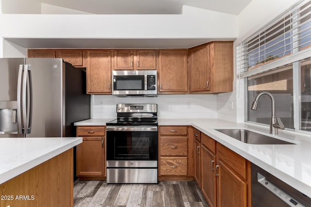 kitchen featuring stainless steel appliances, a sink, light countertops, and brown cabinets