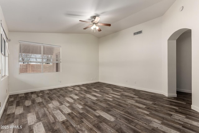 unfurnished room featuring a ceiling fan, arched walkways, dark wood finished floors, baseboards, and vaulted ceiling