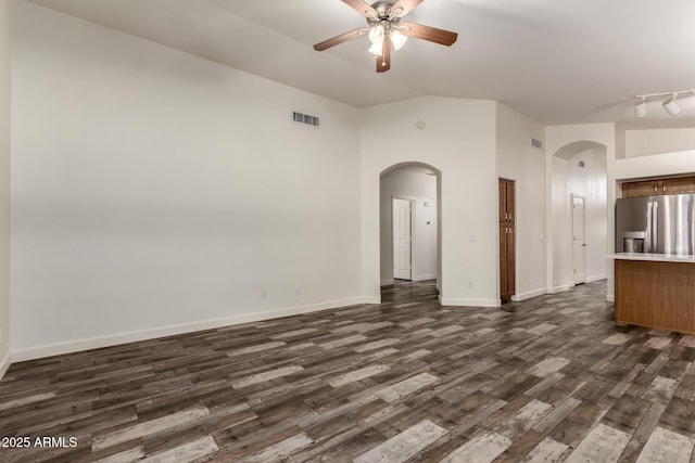 unfurnished living room featuring arched walkways, lofted ceiling, ceiling fan, and dark wood-type flooring