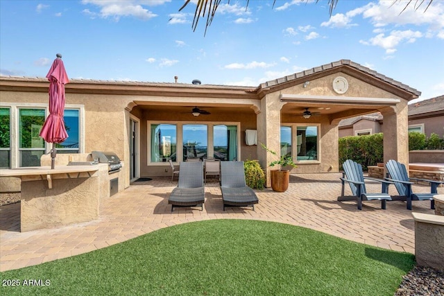 rear view of house featuring ceiling fan, exterior kitchen, and a patio area