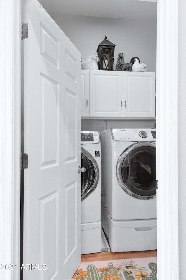 laundry room featuring cabinets, light wood-type flooring, and independent washer and dryer