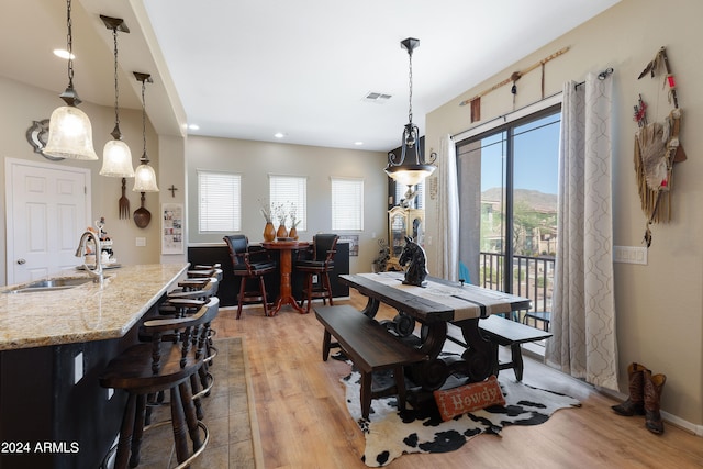 dining area featuring light wood-type flooring, a mountain view, a wealth of natural light, and sink