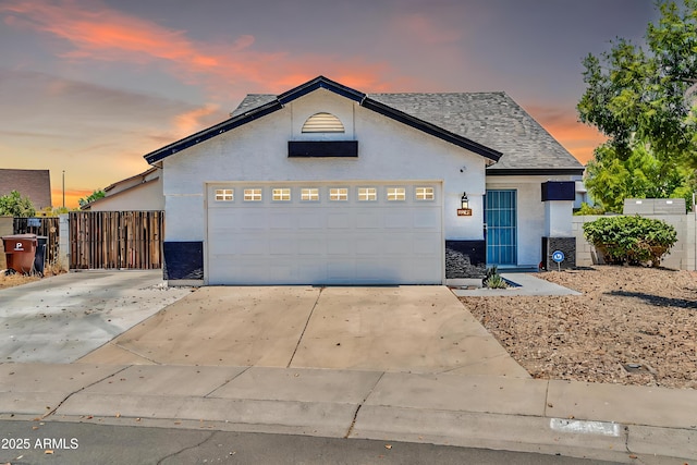 view of front of house featuring concrete driveway, fence, a gate, and stucco siding