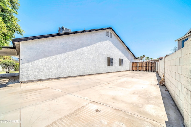 rear view of house featuring a patio area, fence, and stucco siding